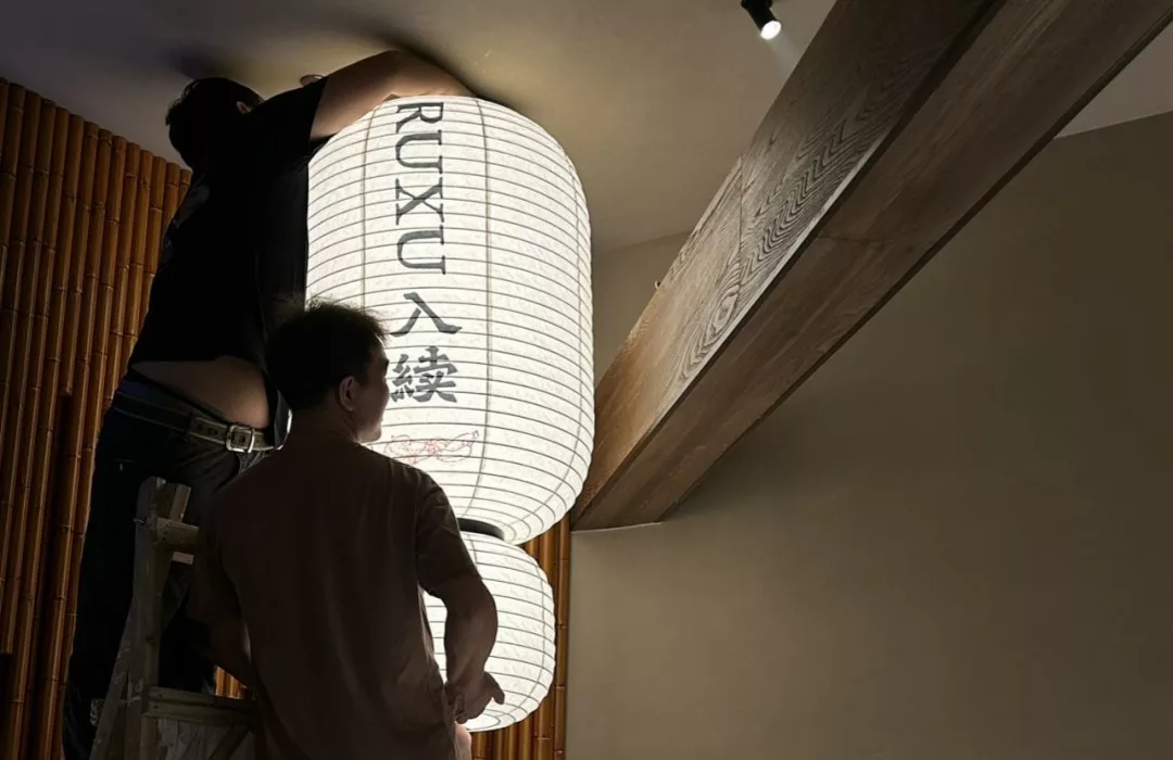 Team positioning the custom rice-paper lantern at RUXU Sugar House