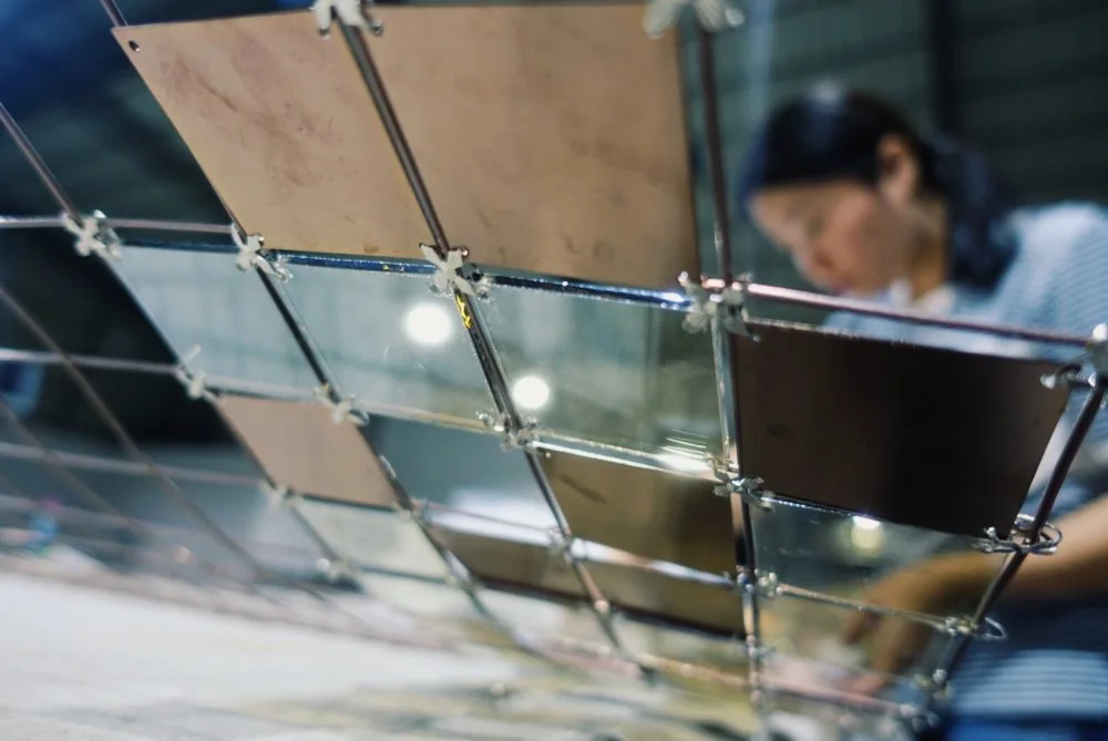 Our custom-lighting team craftspeople assembling reflective panels on a metal lighting frame
