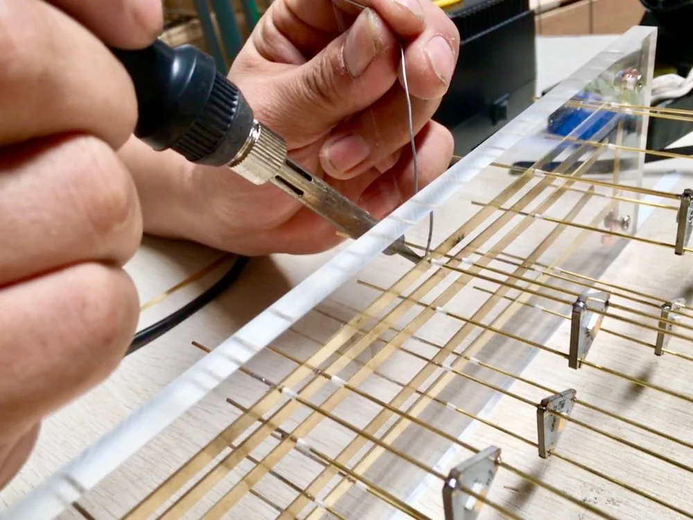 A craftsperson fixing metal components during lighting assembly