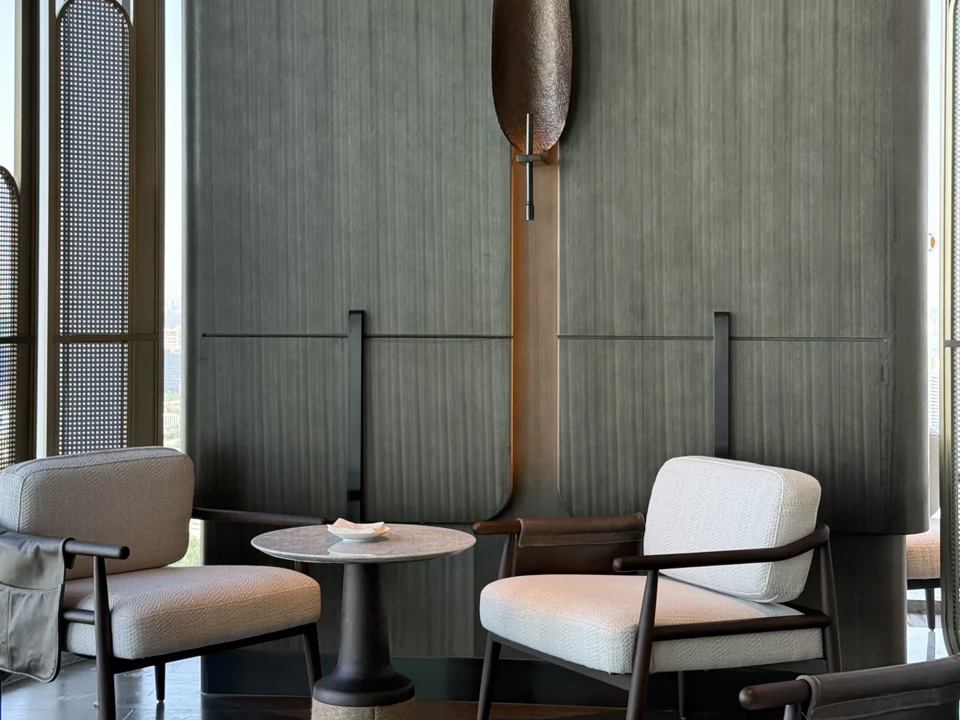 Hotel lounge seating with small tables and pendant lights