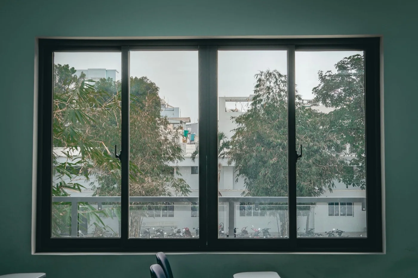 Three-panel aluminium window on a green wall