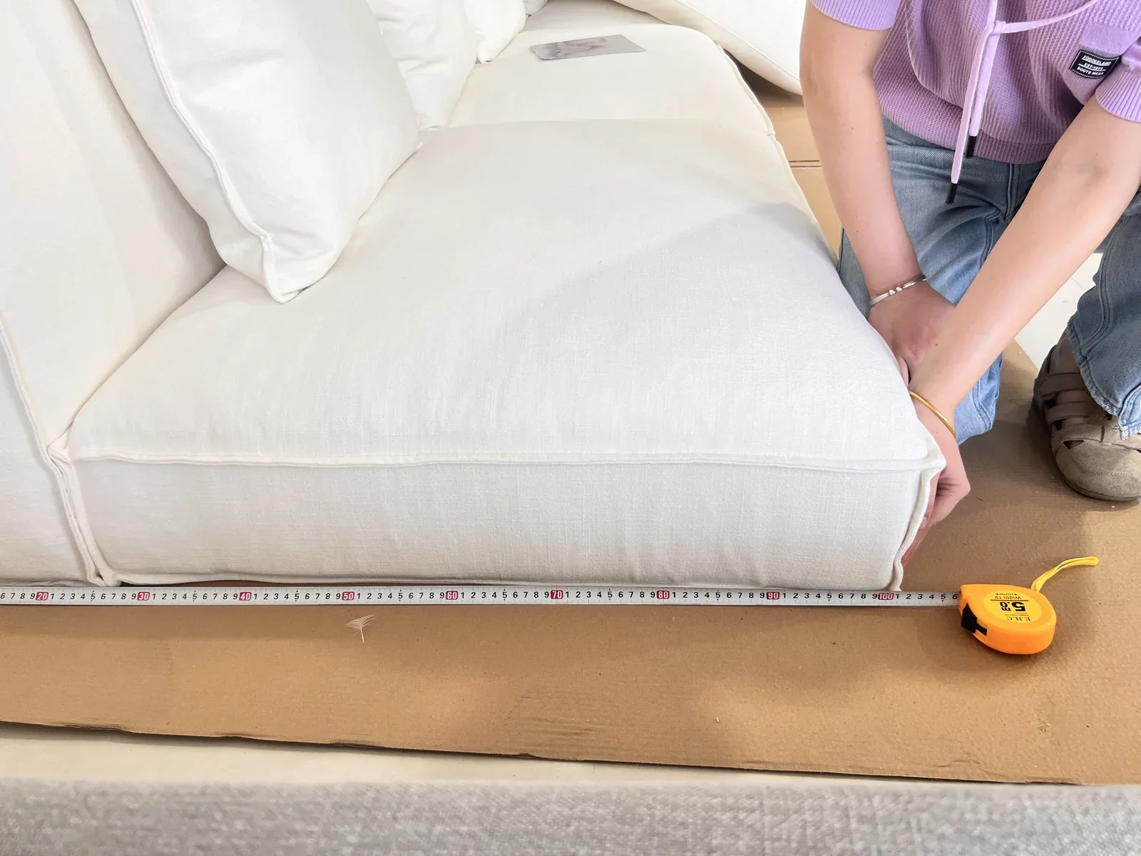 Measuring a white upholstered sofa with a tape measure